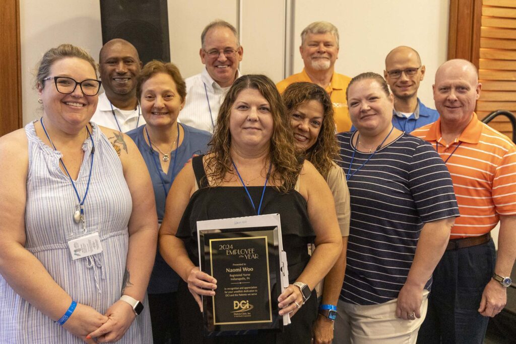 DCI team congratulating employee of the year holding plaque